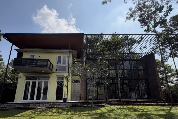 Exterior of a two-storey landed home with a lawn and a glass-walled extension